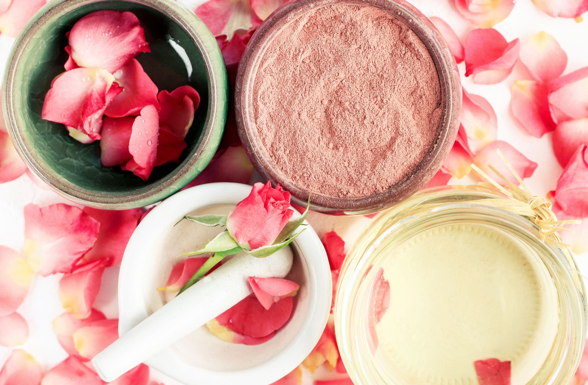 Closeup on bowls viewed above with natural cosmetic ingredients: red clay powder mask